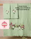 Two green bath towels with floral designs hanging on a rack against a neutral background.