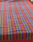 Bed with a colorful striped bedspread in a bedroom setting.