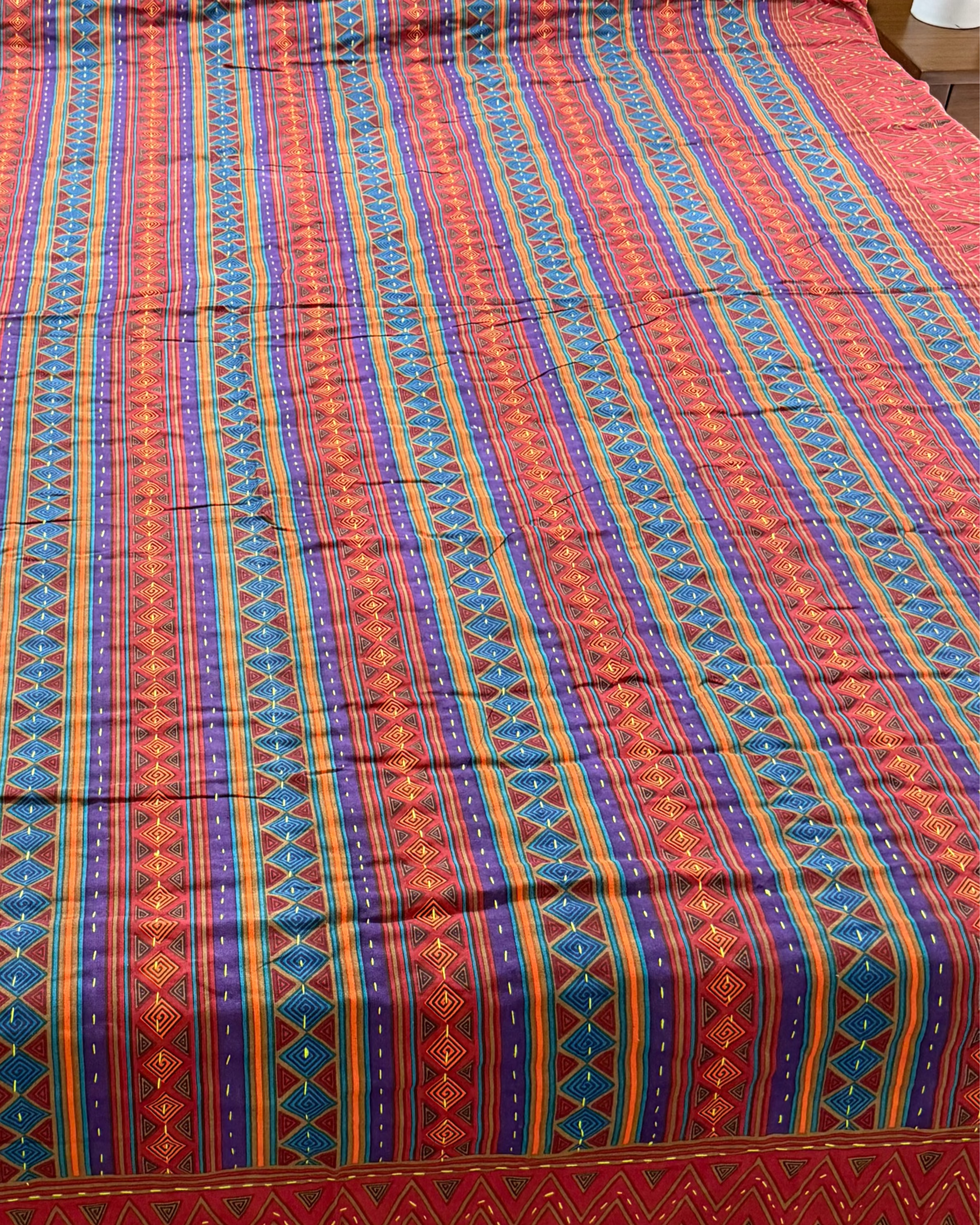 Bed with a colorful striped bedspread in a bedroom setting.