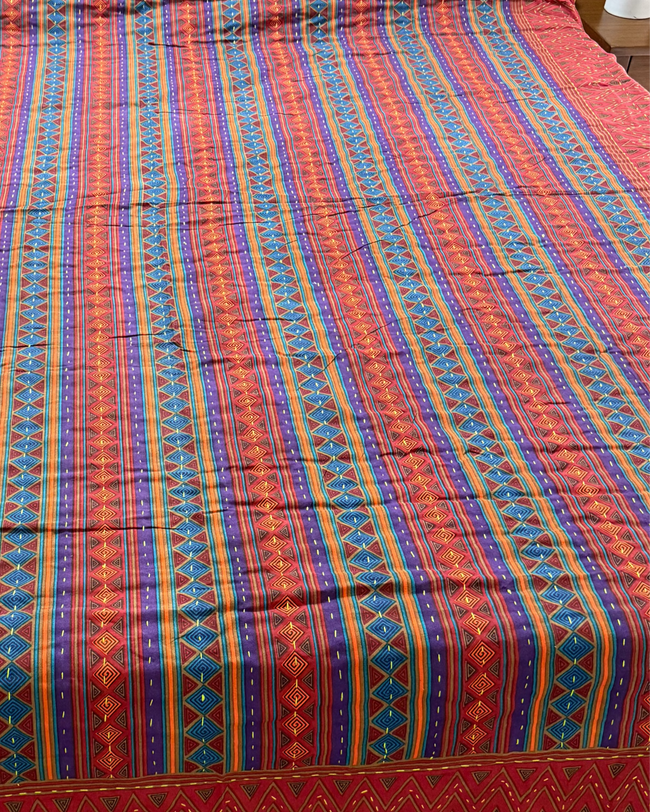Bed with a colorful striped bedspread in a bedroom setting.