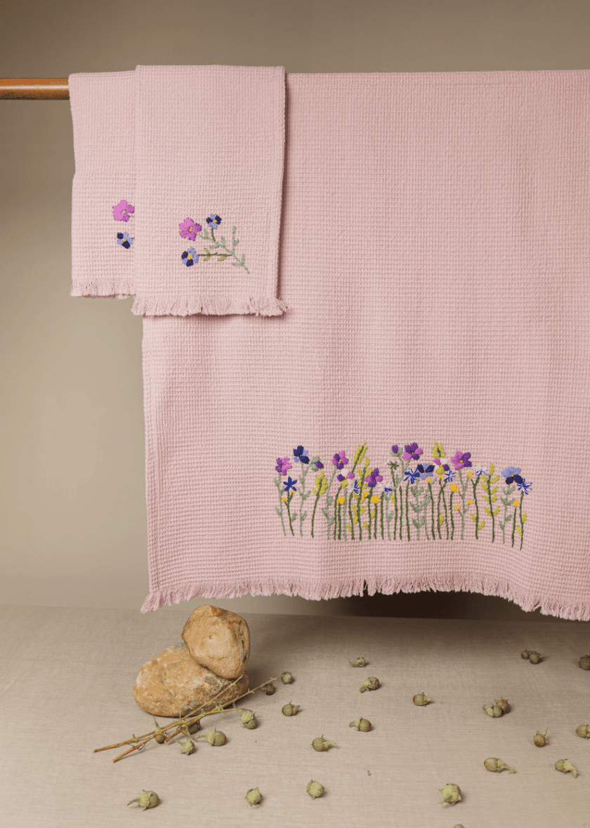 Pink embroidered towels on a wooden surface with a blurred background