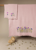 Pink embroidered towels on a wooden surface with a blurred background